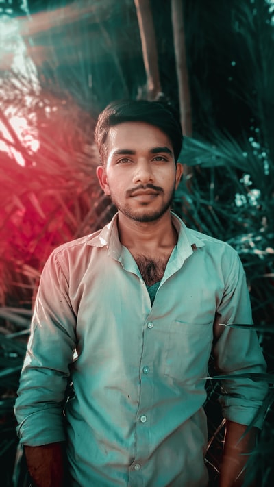 Dressed in a brown button shirt man standing near the green plants
